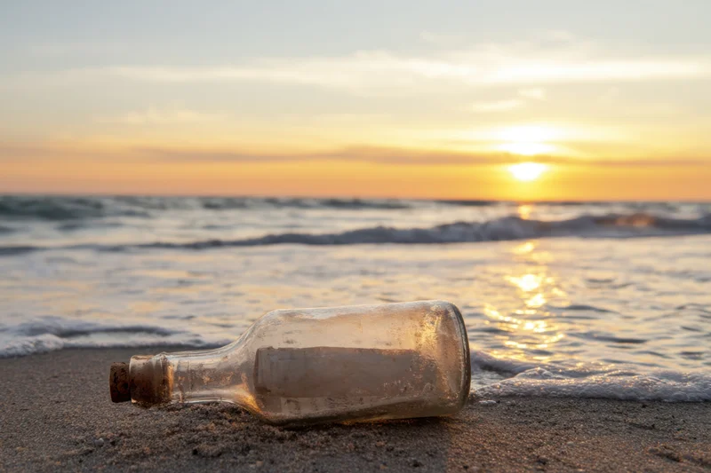 Of a glass bottle washed up on a sandy beach containing a roll
