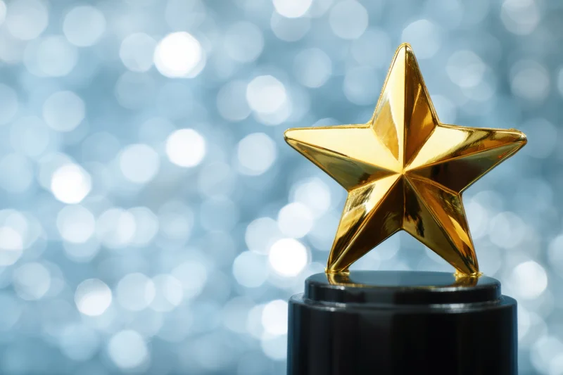 Gleaming gold star trophy atop a sleek black base with blurred bokeh background