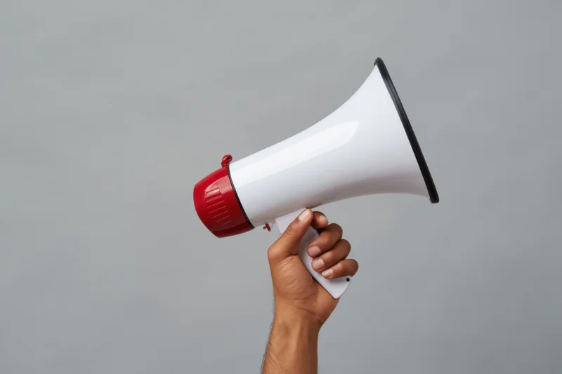Hand holding a white and red megaphone against a gray background