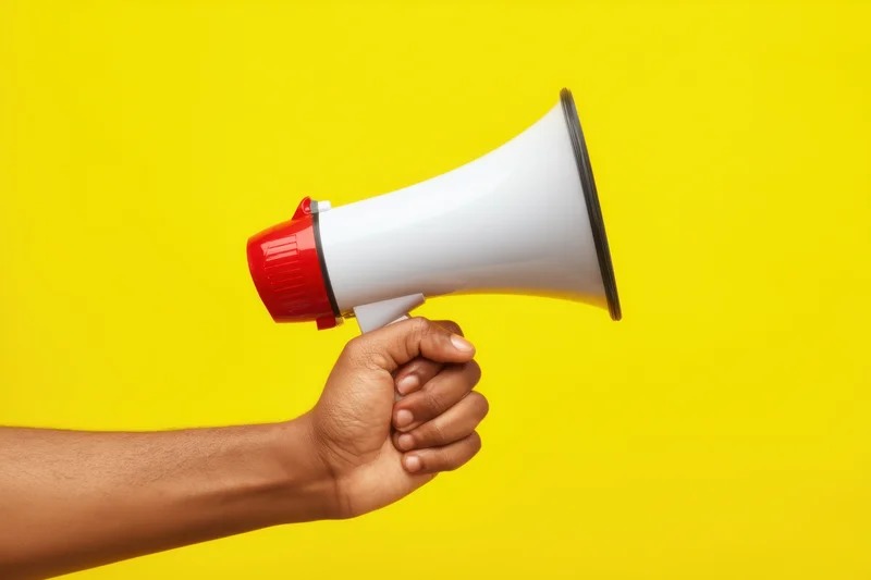 Hand holding megaphone against vibrant yellow background