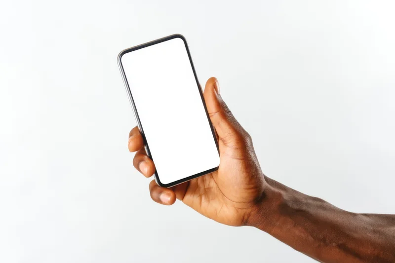 Hand holding a sleek modern smartphone with blank white screen against white background