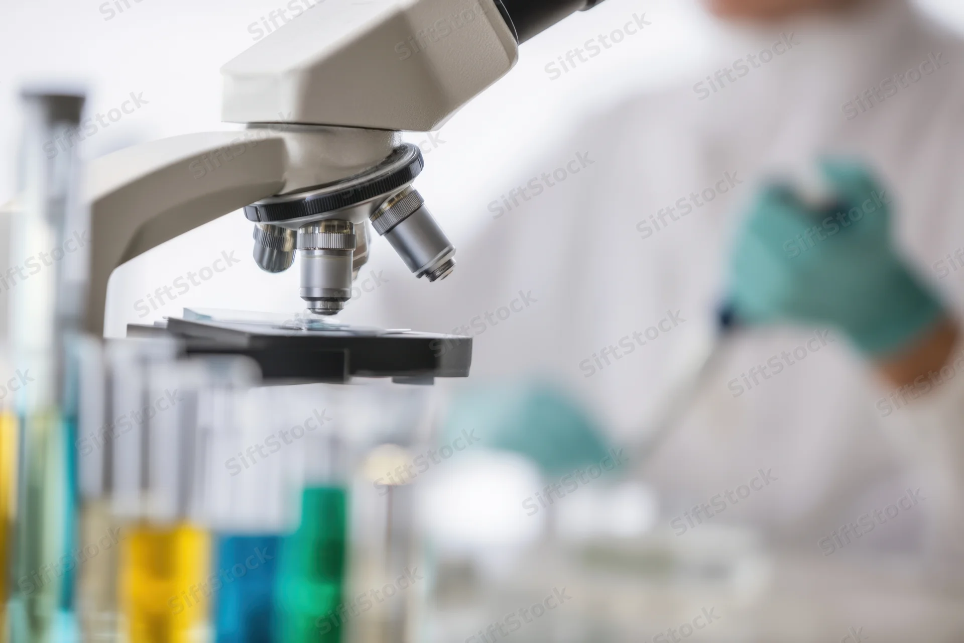 Microscope in focus with test tubes and lab equipment in a research laboratory setting