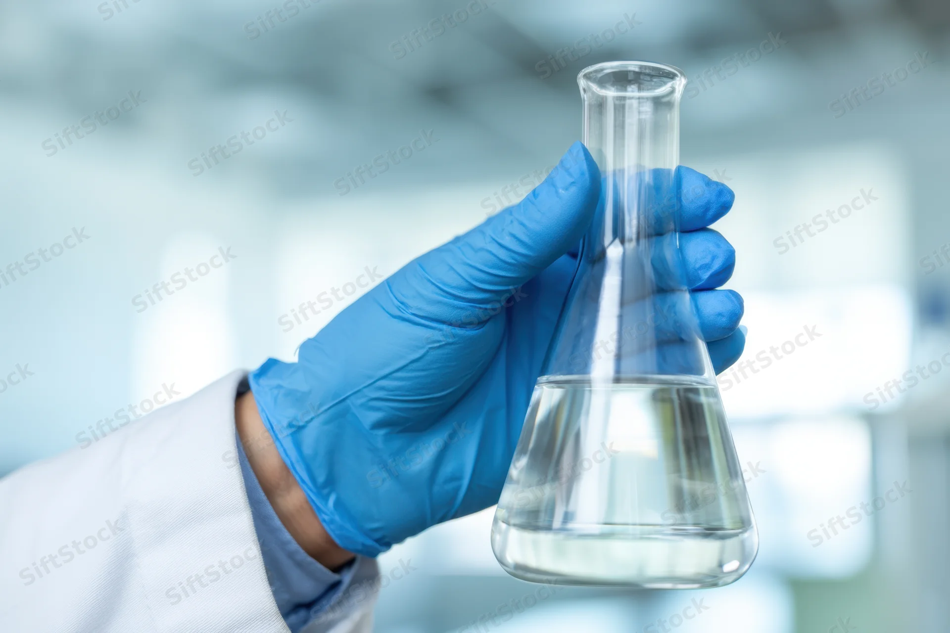 Scientist holding a conical flask with clear liquid in a laboratory setting