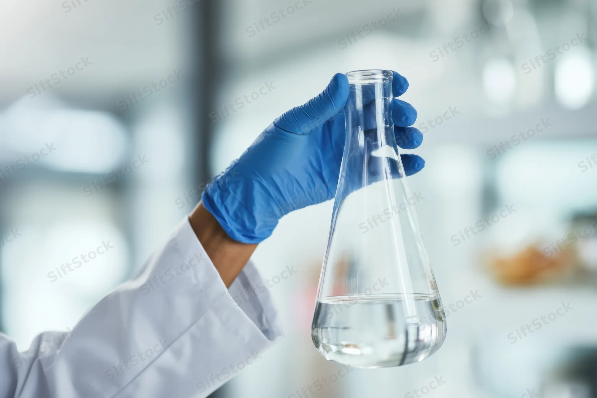 Scientist holding a conical flask with clear liquid in a laboratory setting