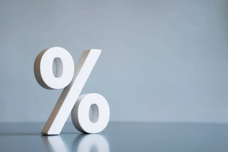Large white percentage symbol standing on a reflective gray surface with copyspace to the right