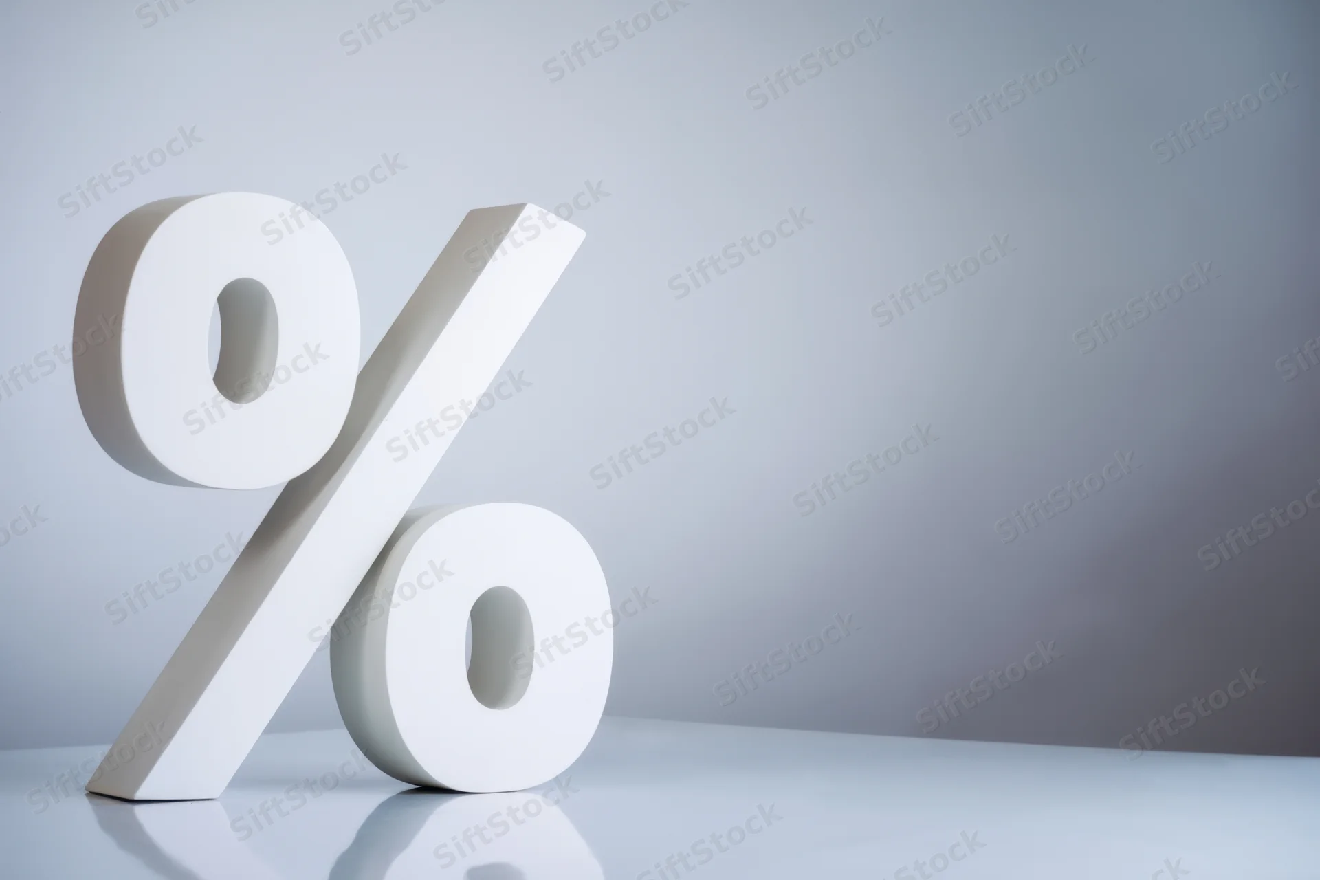 Large white percentage symbol standing on a reflective surface with copyspace to the right