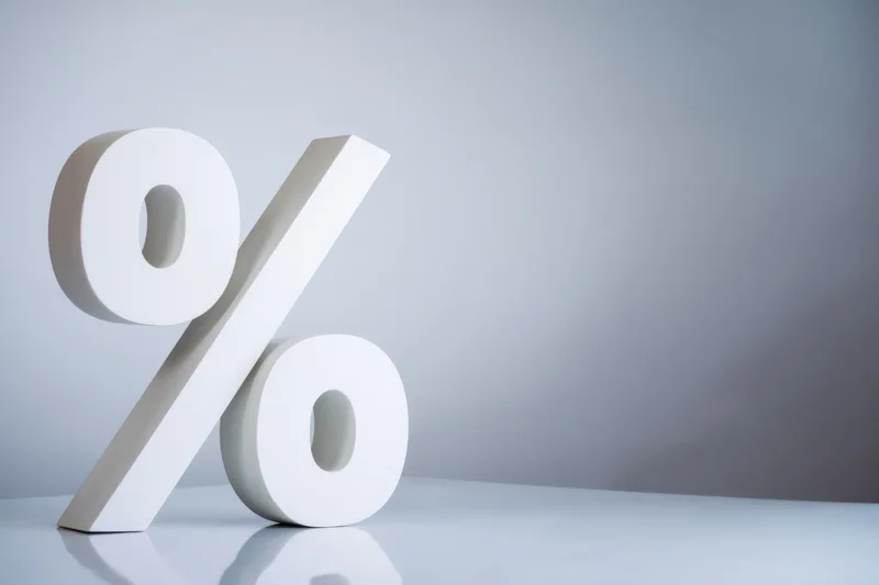 Large white percentage symbol standing on a reflective surface with copyspace to the right