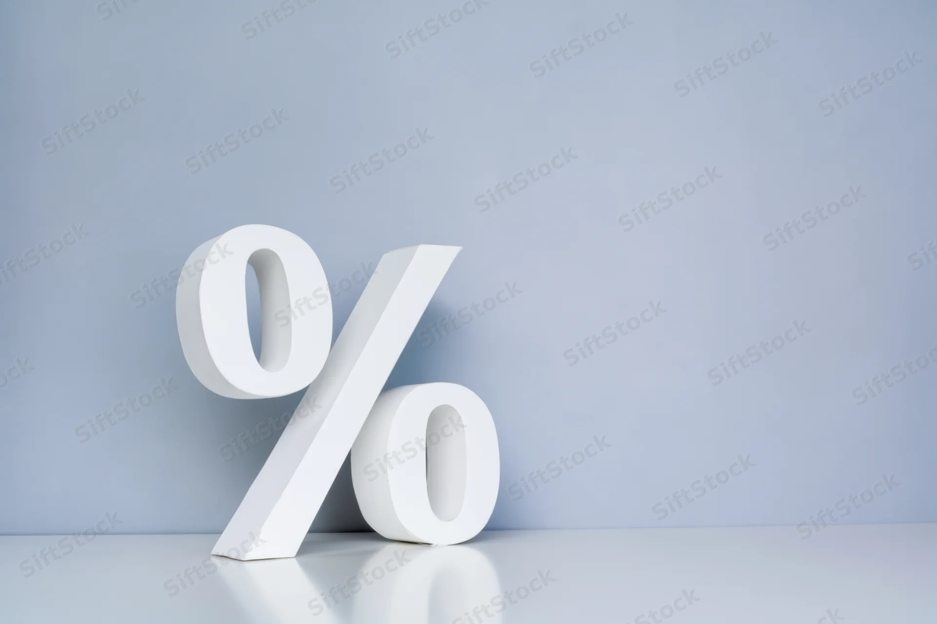 Large white percentage symbol standing on a reflective surface against a light blue background