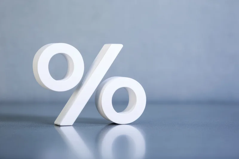 Large white 3d percentage symbol standing on a reflective gray surface with copyspace
