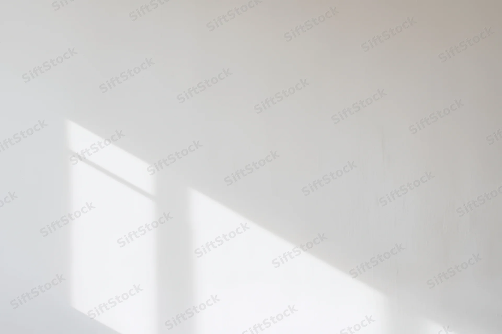 Soft shadows from a window cast across a white interior wall