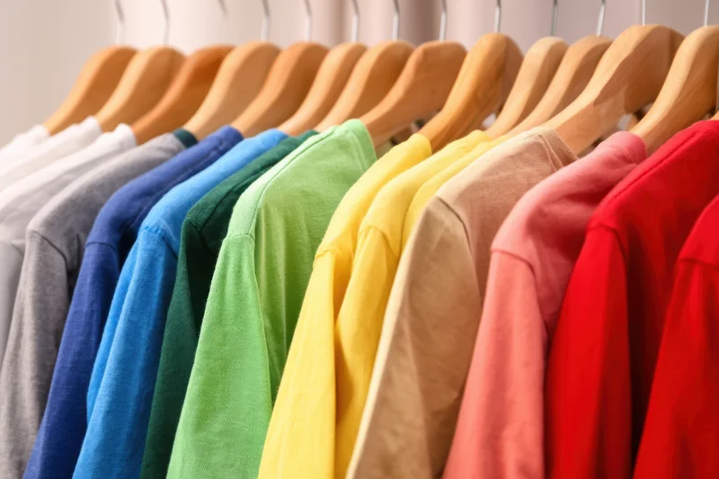 Colorful t-shirts neatly arranged on wooden hangers in a retail display