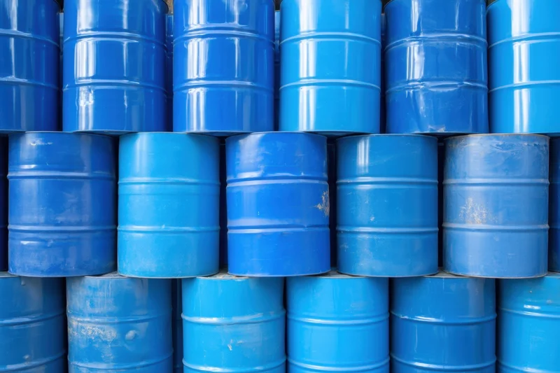 Blue metal barrels stacked in neat rows in a warehouse storage area
