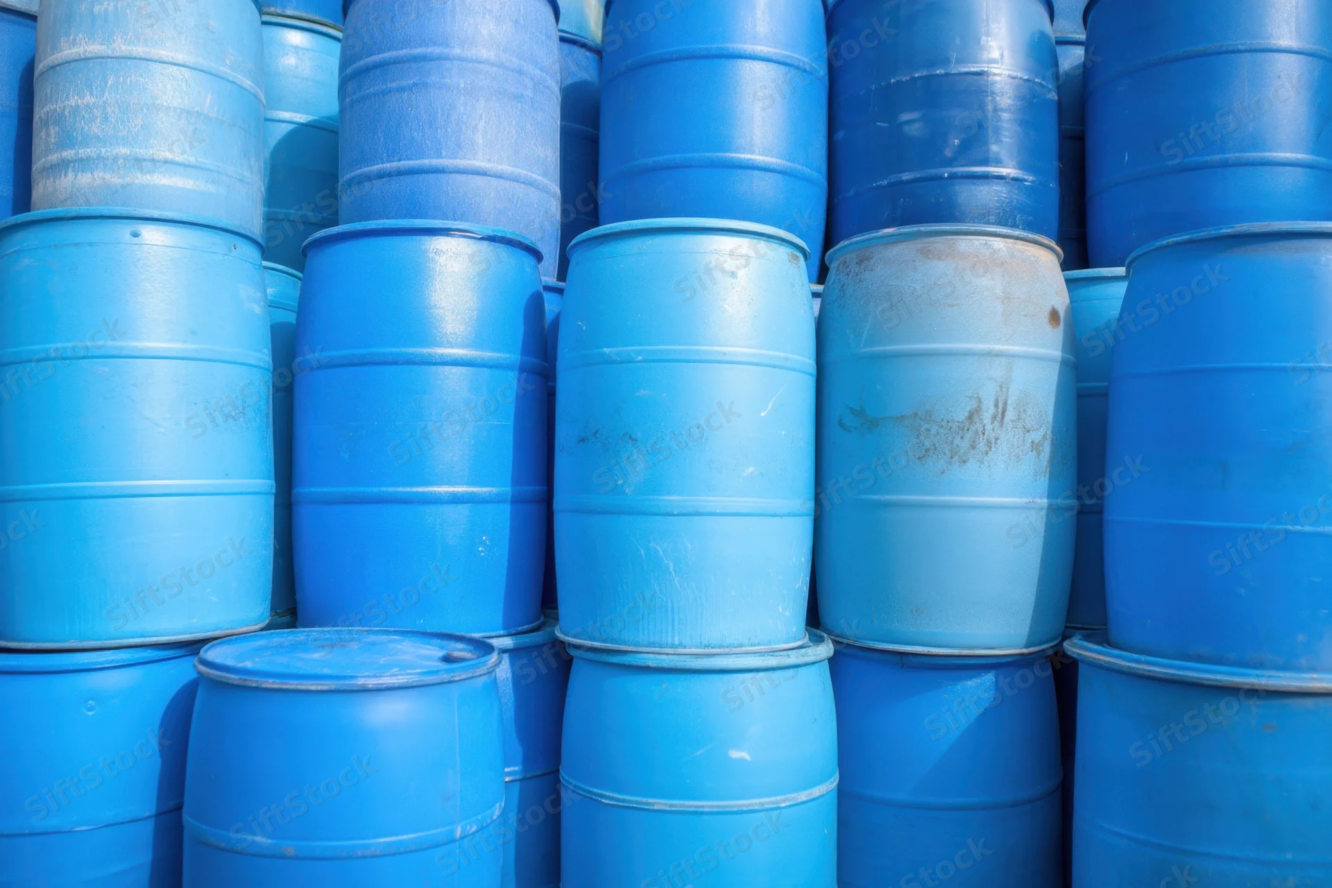 Blue plastic barrels stacked in neat rows in a warehouse storage area