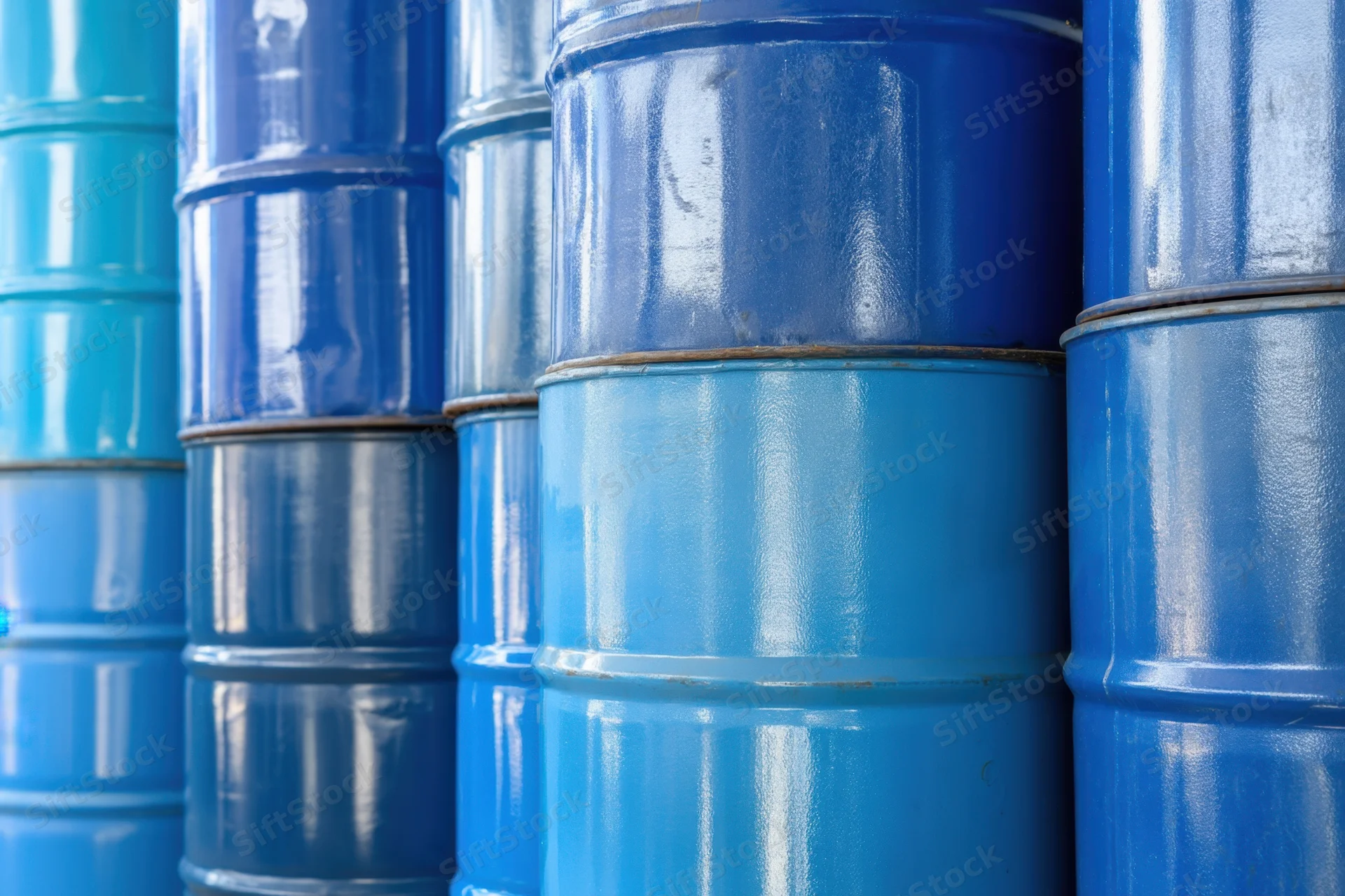 Blue metal barrels stacked in neat rows in an industrial storage area