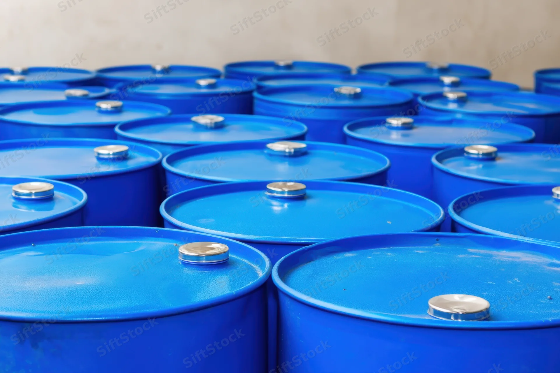 Bright blue metal barrels stacked in neat rows inside a warehouse interior