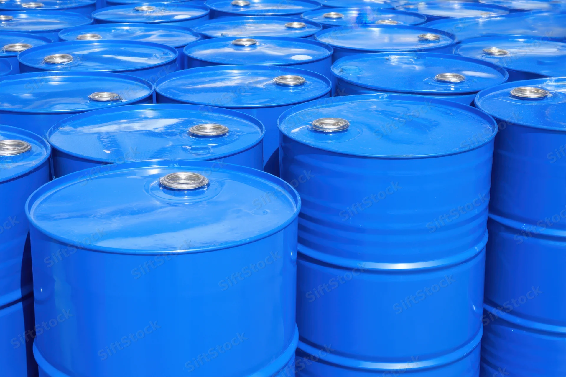 Bright blue metal barrels stacked neatly in rows outdoors