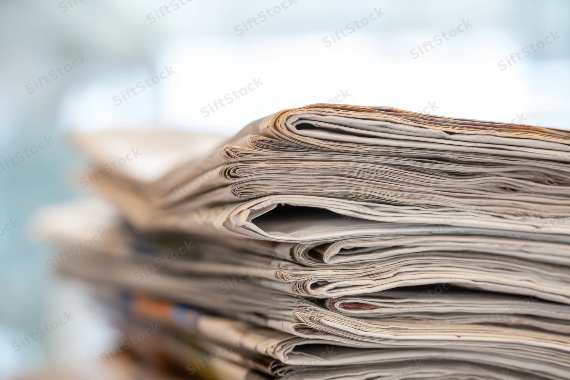 Stack of folded newspapers arranged vertically with visible creases and layered edges
