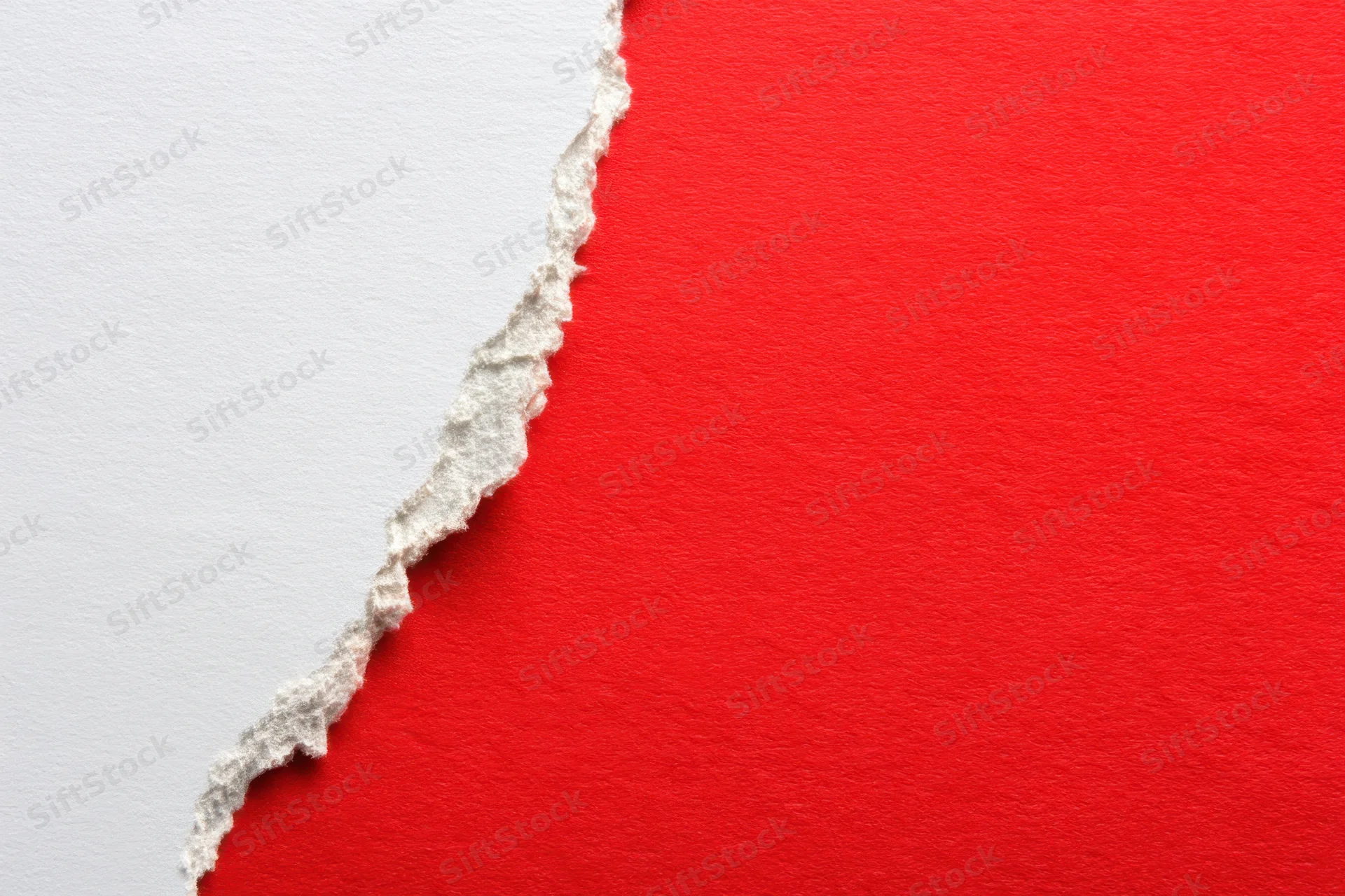 Torn white paper revealing red surface with textured edge