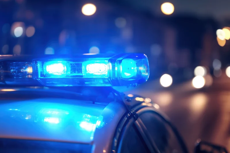 Close-up of flashing blue police car light on rooftop at night on wet city street