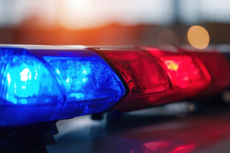 Police lightbar flashing blue and red on vehicle roof at dusk