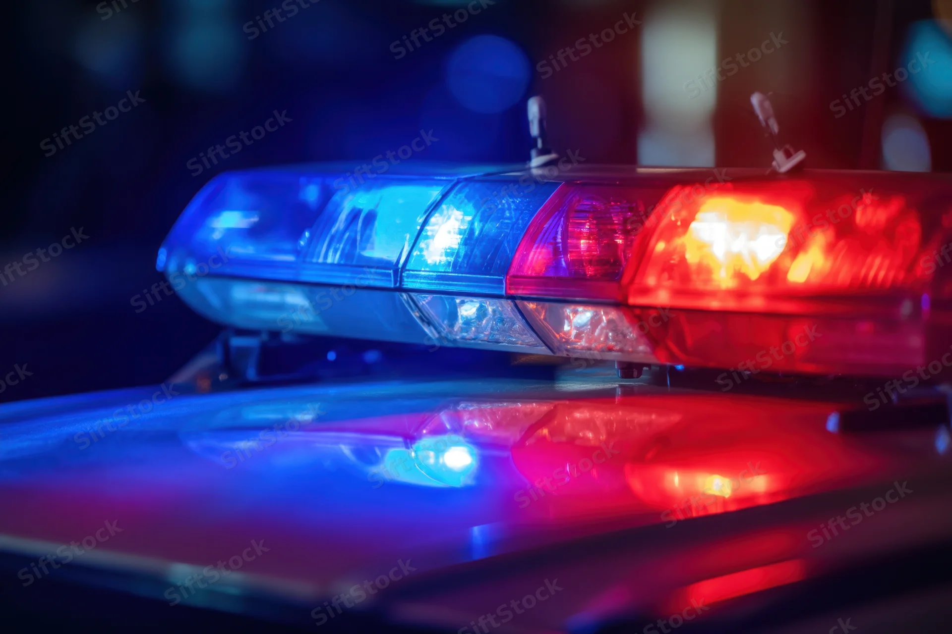 Police lightbar flashing red and blue on vehicle rooftop at night