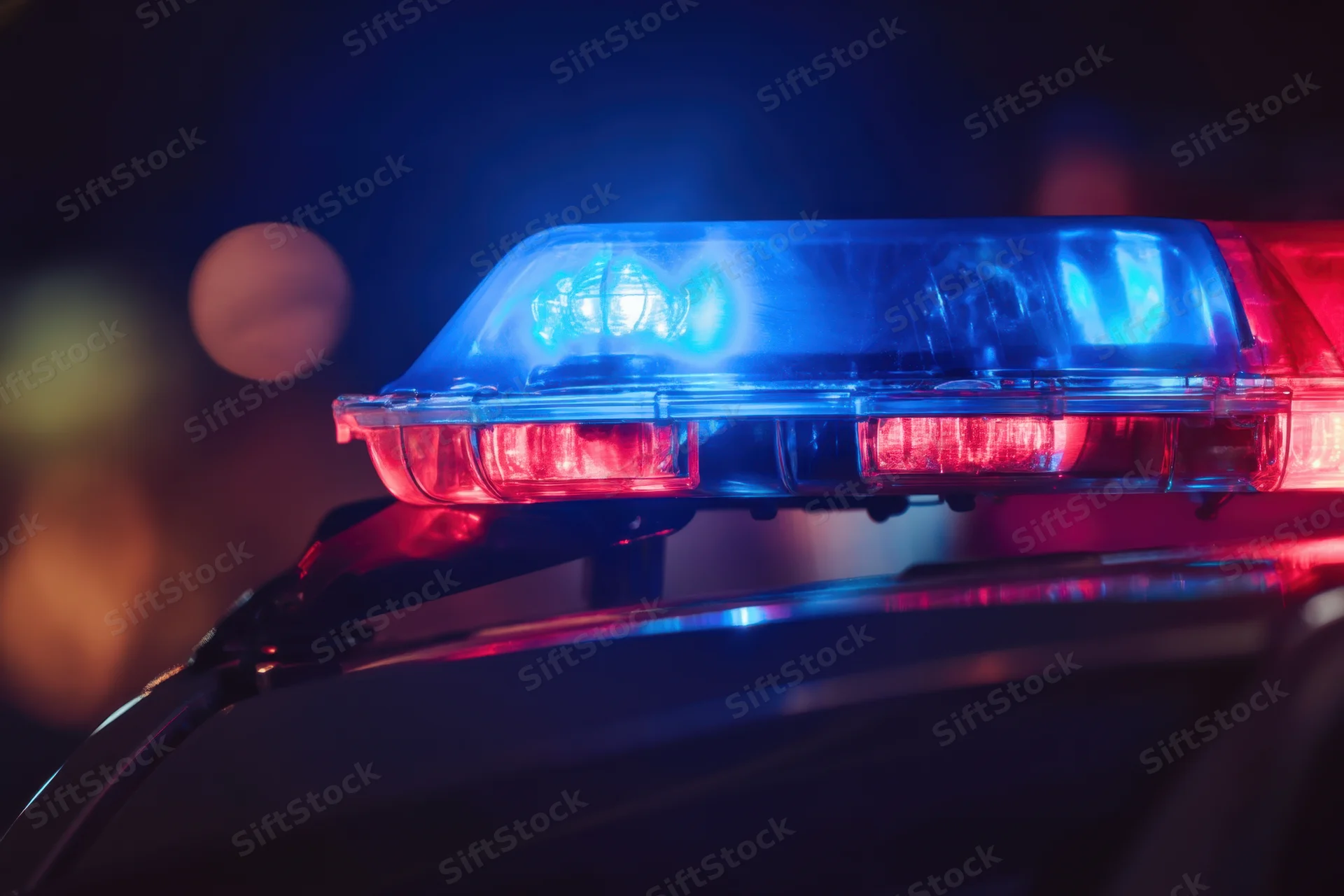 Police car light bar flashing blue and red at night on rooftop
