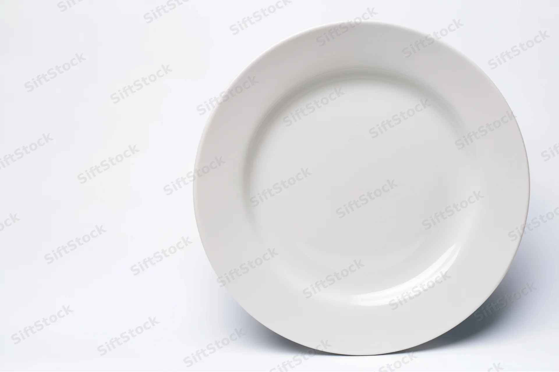 White ceramic plate resting on plain white surface with copyspace