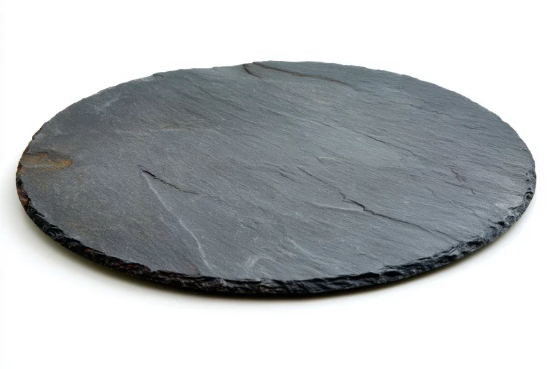 Round textured black slate serving plate with rustic edges on white background