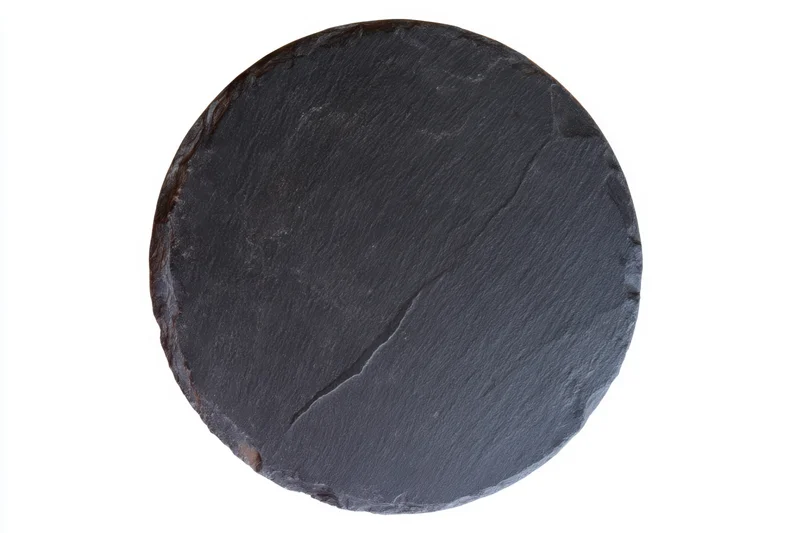 Round black slate serving plate with textured rustic surface isolated on white