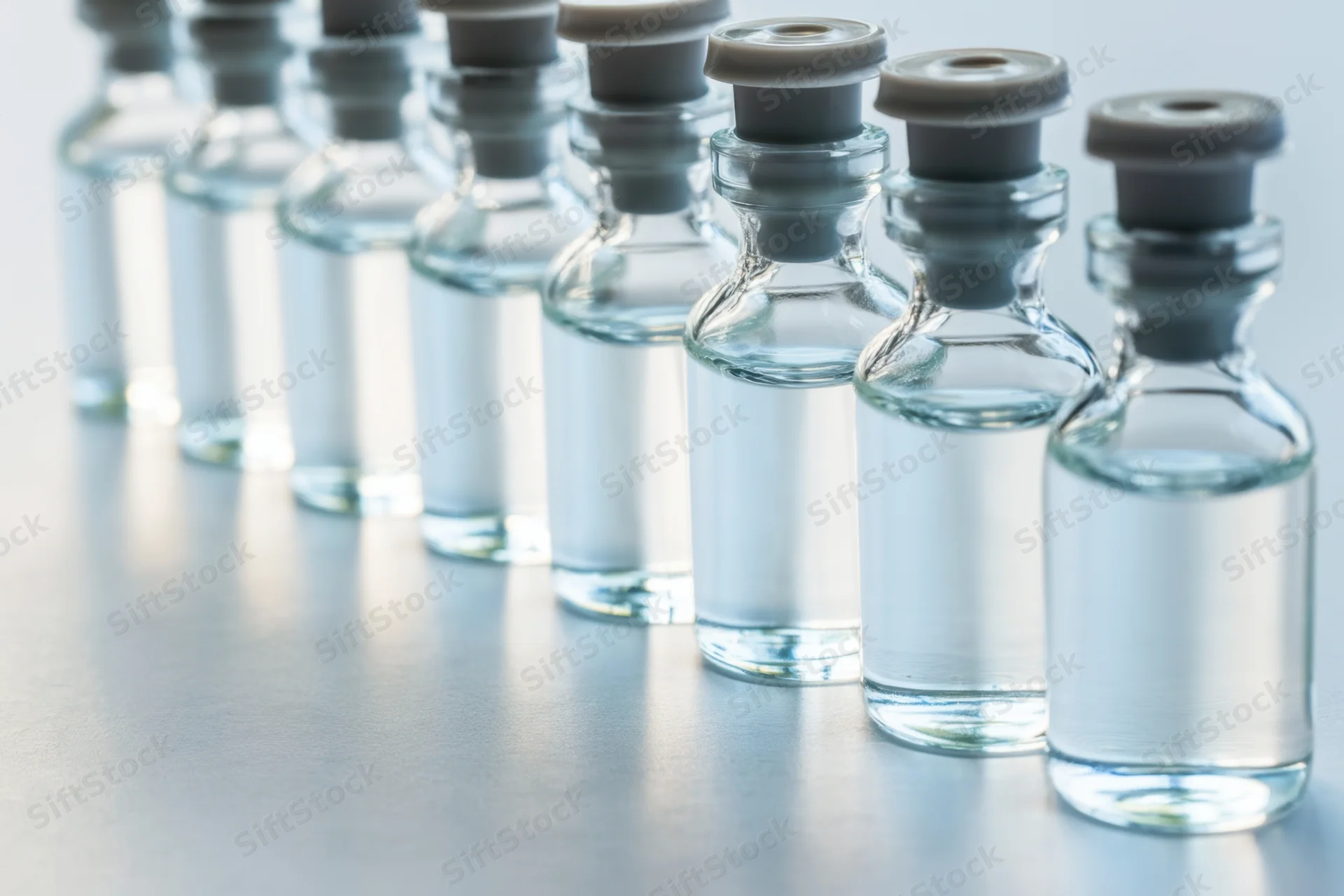 Row of glass vials filled with clear liquid capped in a lab setting