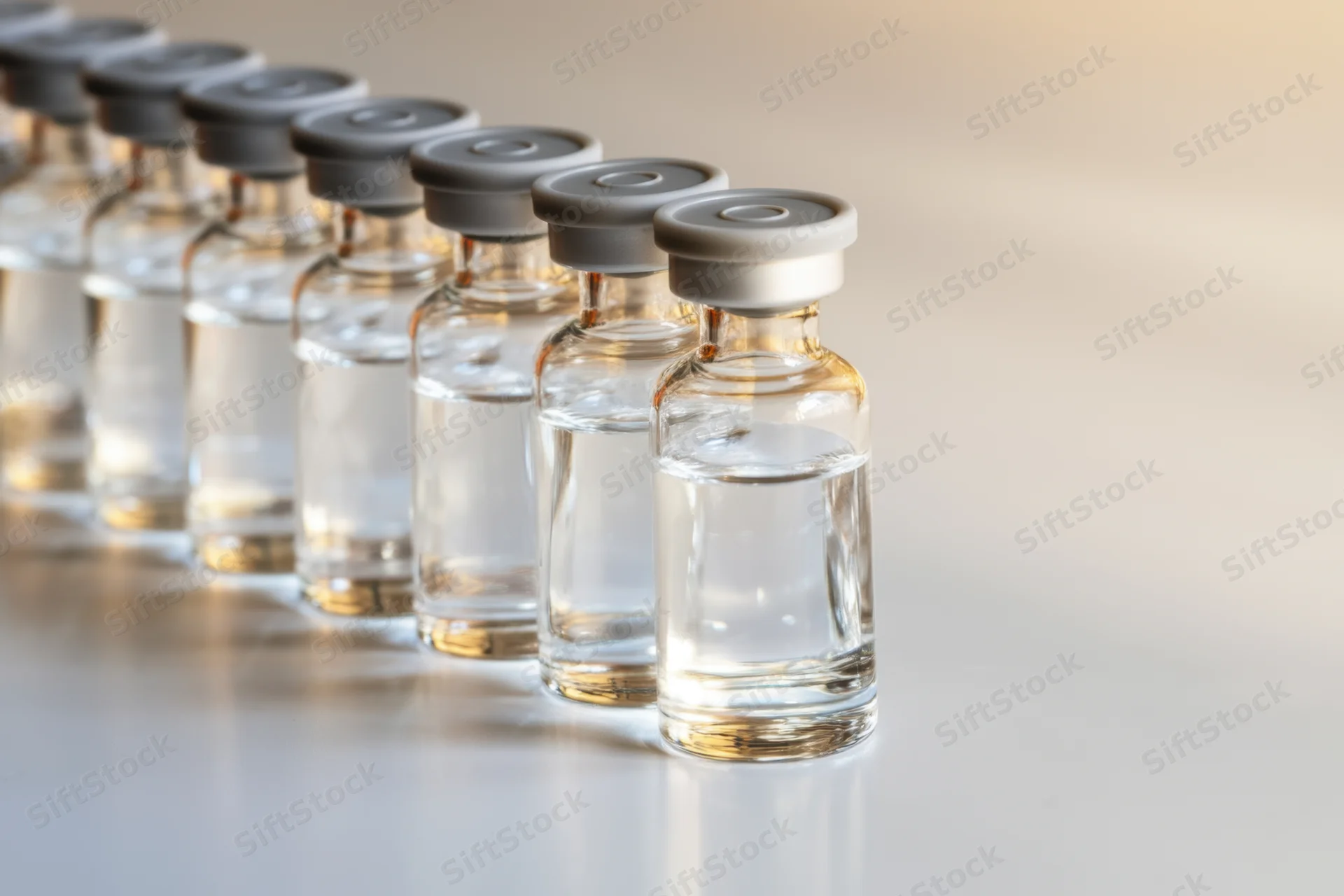 Row of glass vials filled with clear liquid capped in a laboratory setting