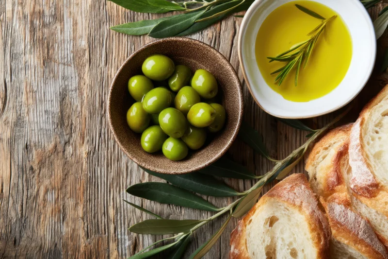 Green olives and olive oil with bread on a rustic wooden table