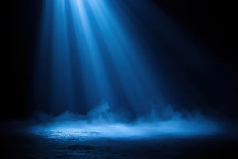 Soft blue light beams shining down through mist onto dark water surface