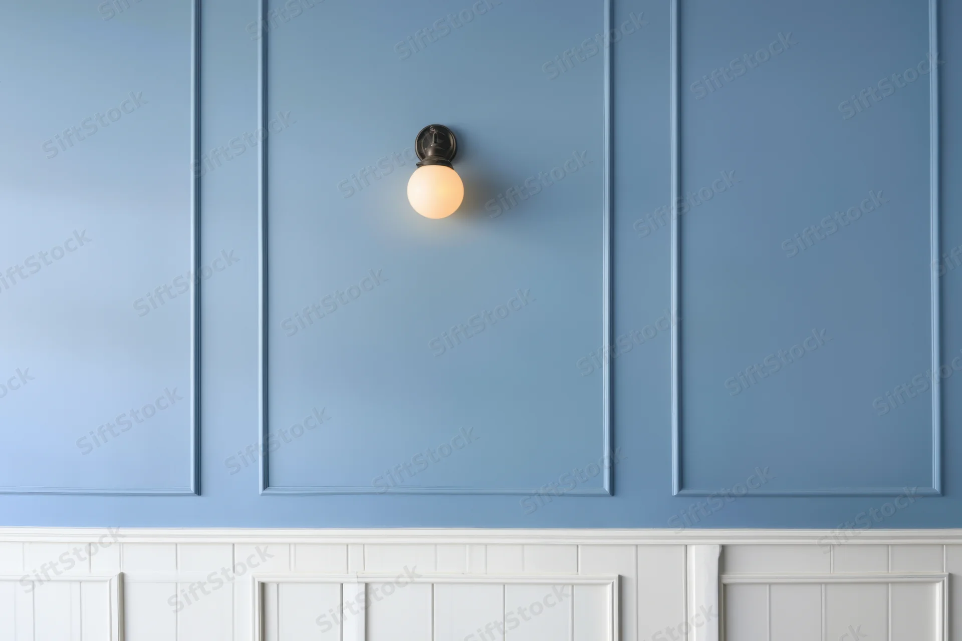 Blue paneled wall with a warm glowing sconce light above white wainscoting