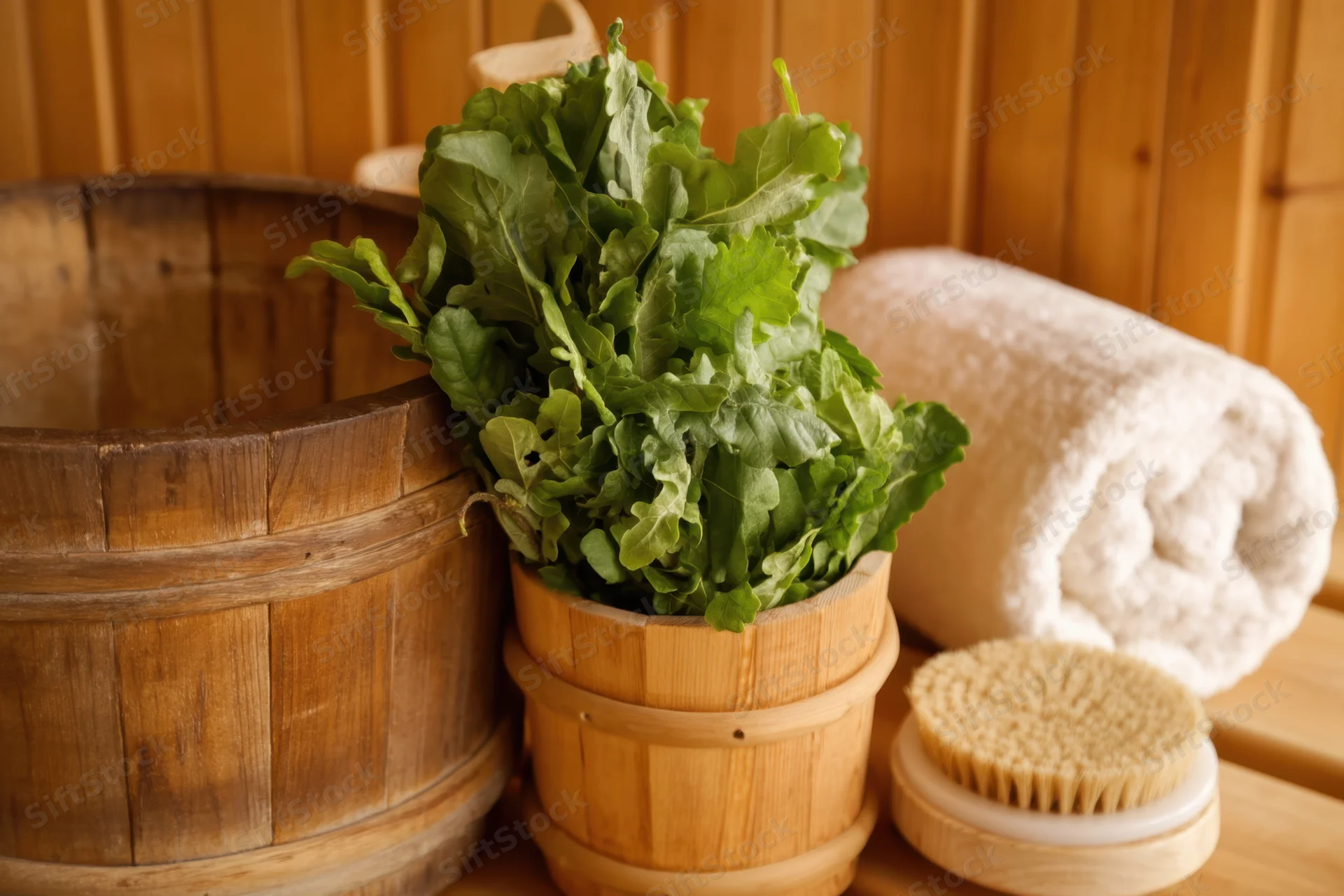 Fresh arugula in a wooden bucket beside a towel and brush in a sauna with wooden walls