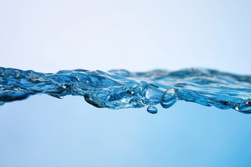 Clear blue water surface with gentle ripples and bubbles against a light blue background