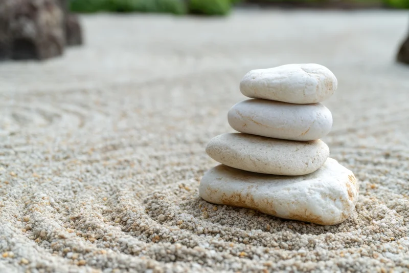Balanced white pebbles stacked in a raked sand zen garden