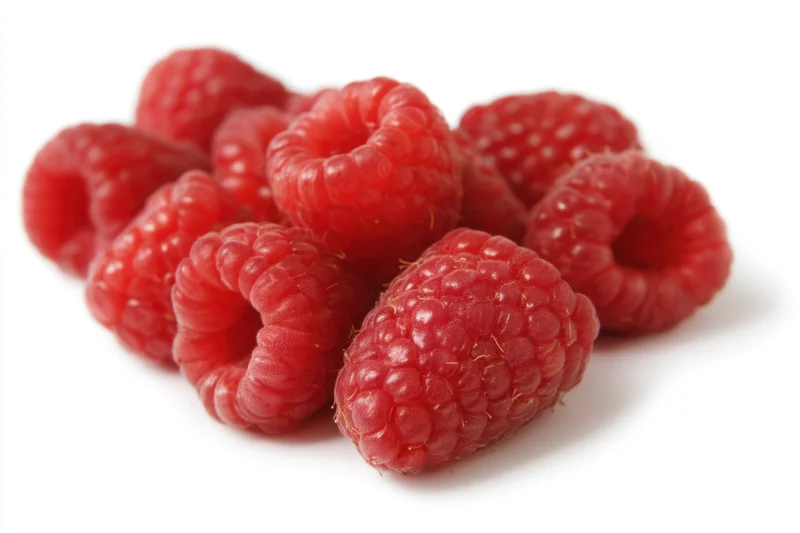 Fresh red raspberries clustered together on a white background