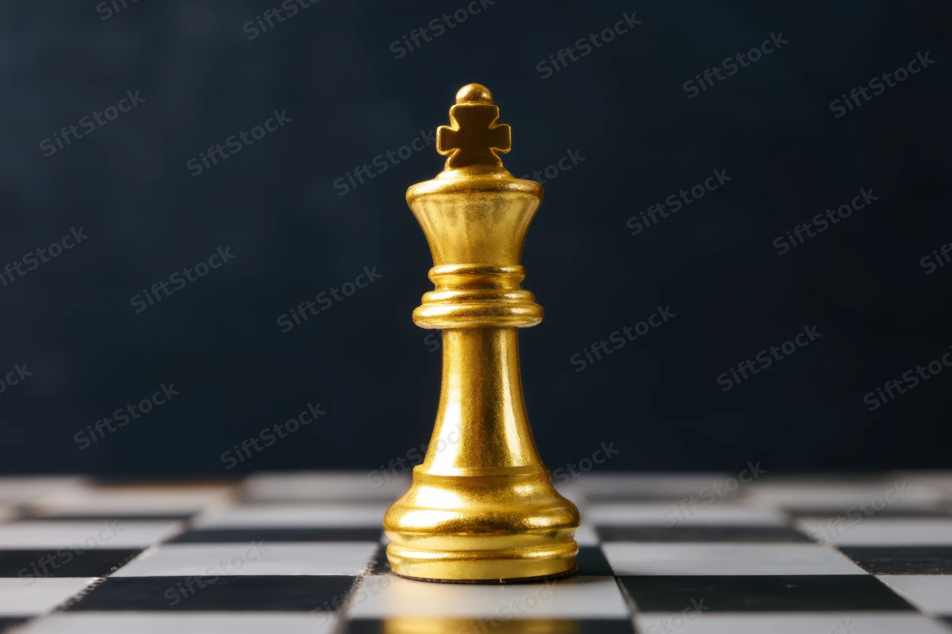 Golden chess king standing on a checkered board against a dark background