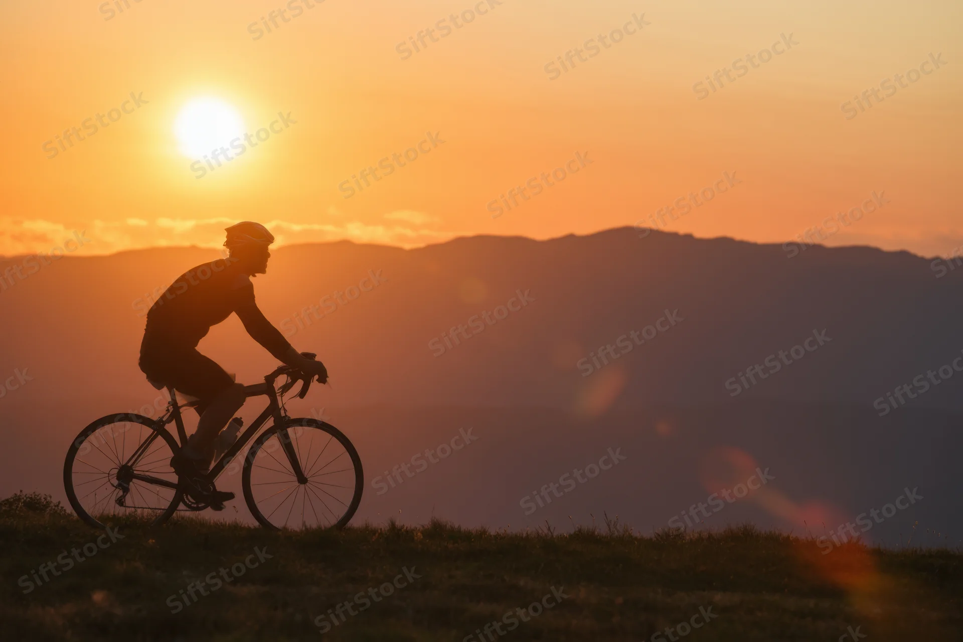 Silhouette of a cyclist riding on a mountain trail at sunset