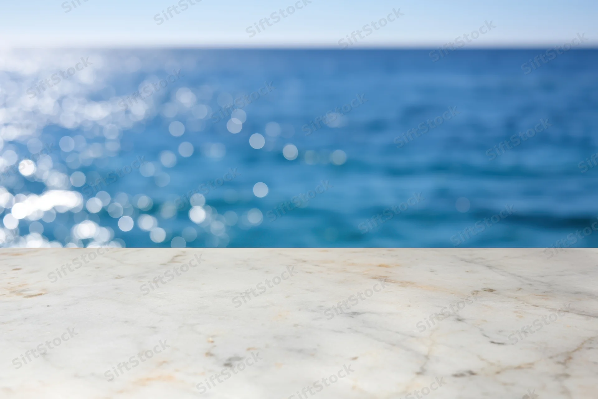 Smooth marble tabletop in foreground with blurred ocean and sky in background