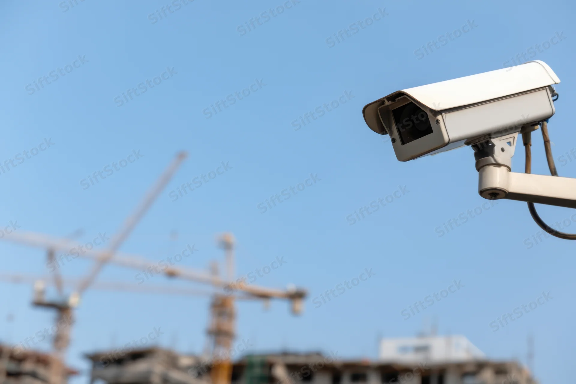 Surveillance camera mounted outdoors overlooking a construction site with cranes and buildings under development