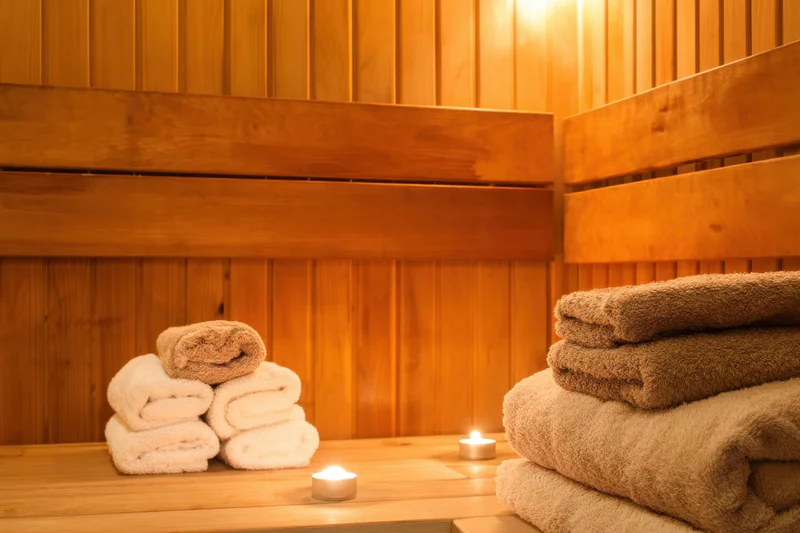 Stacked towels and candles on wooden benches inside a tranquil sauna interior
