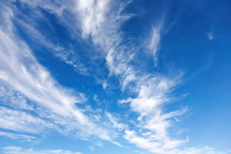 Vast clear blue sky with delicate wispy white clouds scattered across the expanse