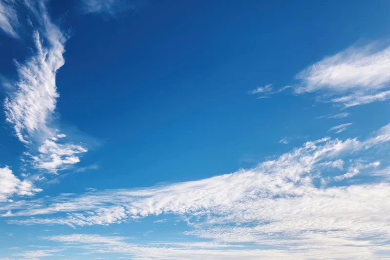 Vast clear blue sky with delicate wispy white clouds scattered across the horizon