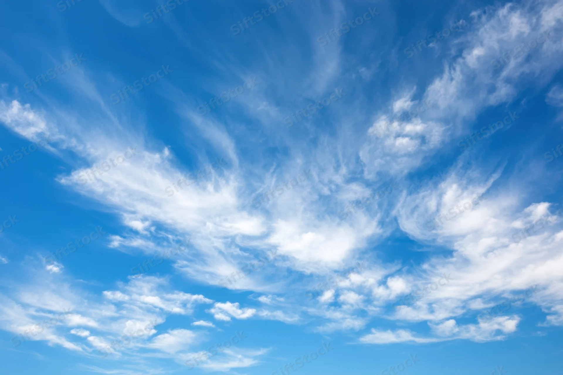 Vast clear blue sky with delicate wispy white clouds scattered across the expanse
