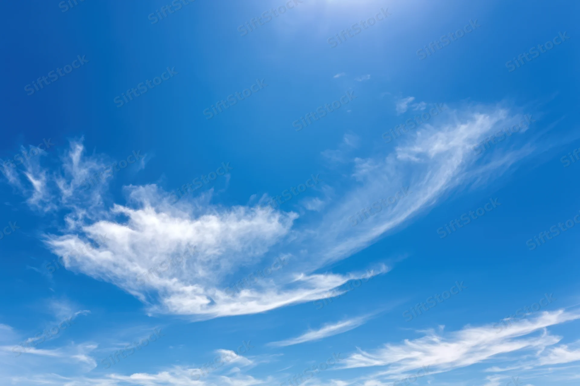 Vast clear blue sky with delicate wispy white clouds scattered across the expanse
