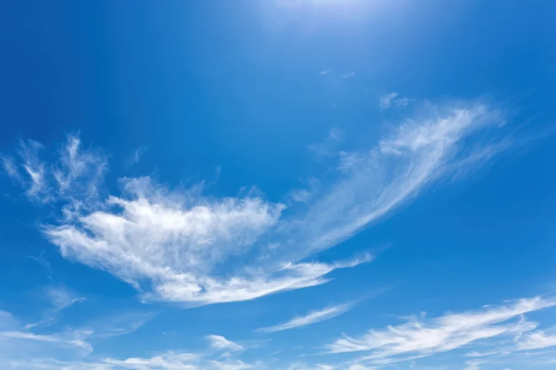 Vast clear blue sky with delicate wispy white clouds scattered across the expanse