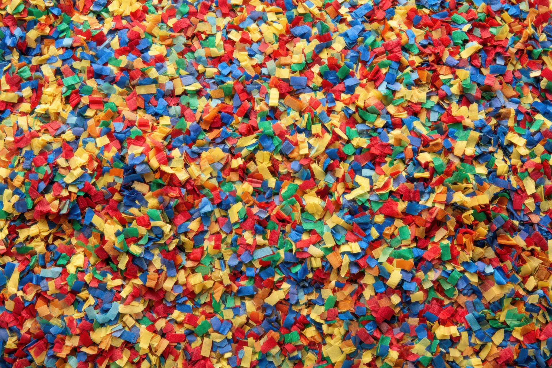 Scattered confetti pieces covering a surface in vibrant colors