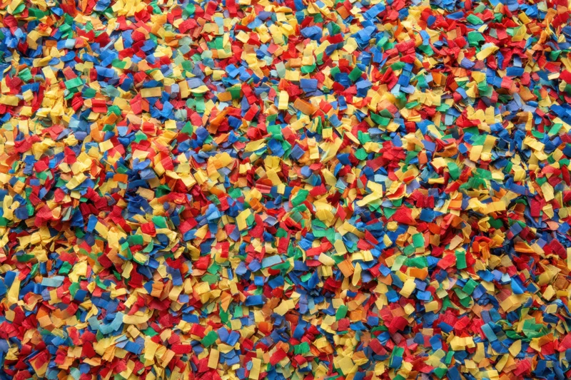 Scattered confetti pieces covering a surface in vibrant colors